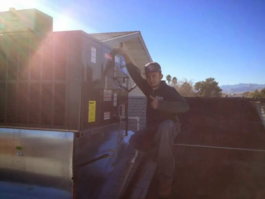 HVAC technician performing AC Tune-Up on a rooftop unit in Roy